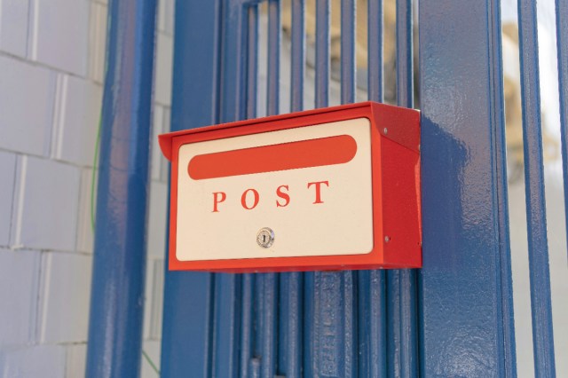 A mailbox against a blue fence