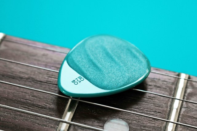 A blue guitar pick in a guitar string