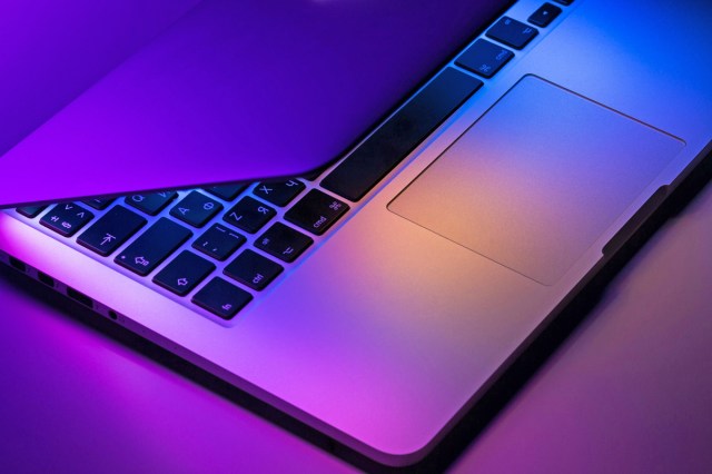 A laptop slightly open with moody purple lighting