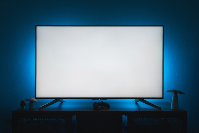 A tv with blue lights on the wall behind it 