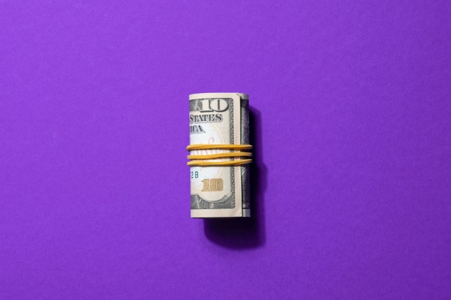 Money rolled up on a purple background